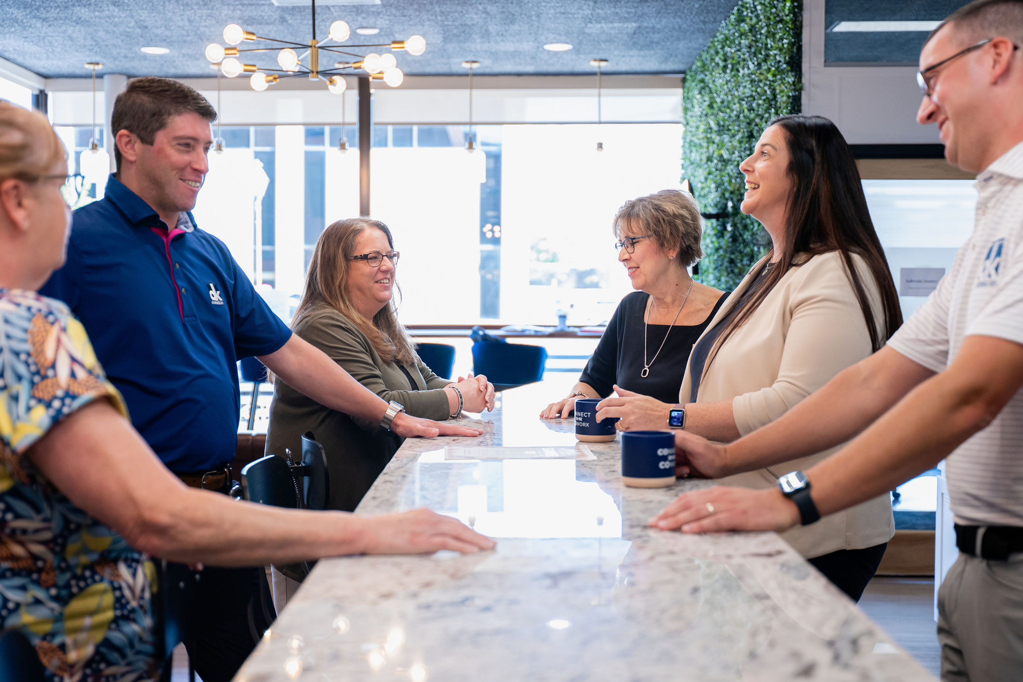 Dostal & Kirk team members smiling and talking during an office meeting around a table